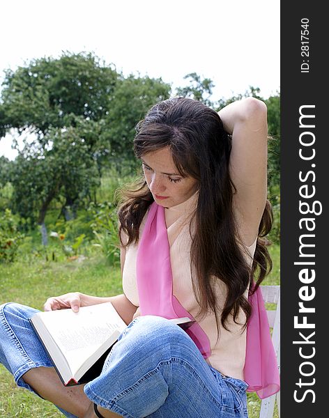 Young woman reading book on meadow