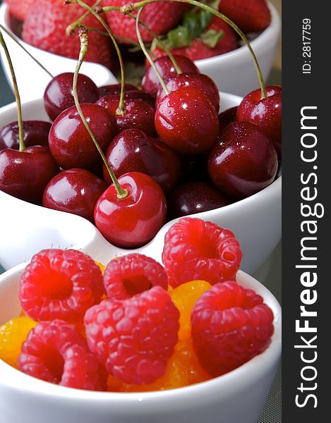 Small white bowls of raspberries, cherries, strawberries, and orange slices. Small white bowls of raspberries, cherries, strawberries, and orange slices.