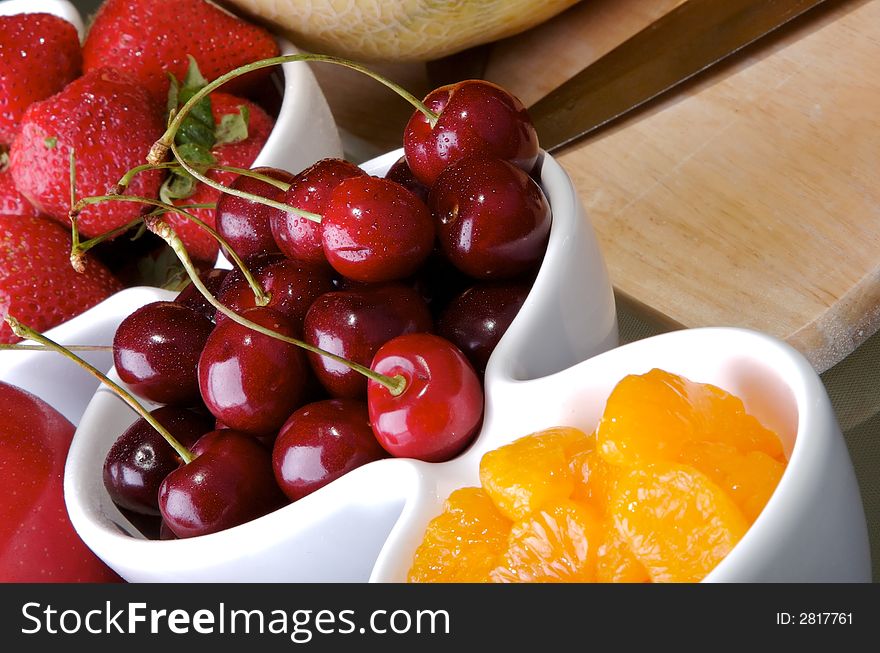 Small white bowls of cherries, strawberries, and orange slices. Small white bowls of cherries, strawberries, and orange slices.