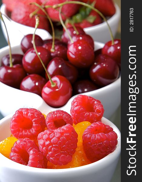 Small white bowls of raspberries, cherries, strawberries, and orange slices. Small white bowls of raspberries, cherries, strawberries, and orange slices.