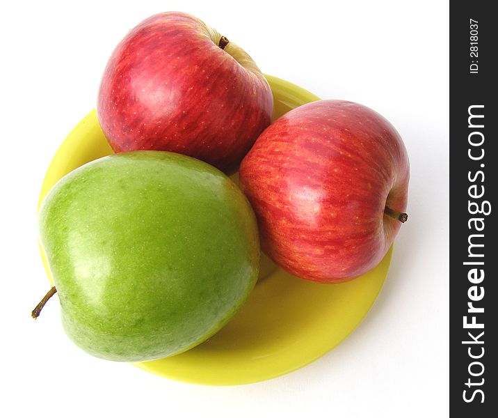 One green and two red apples lay on a yellow plate. One green and two red apples lay on a yellow plate.