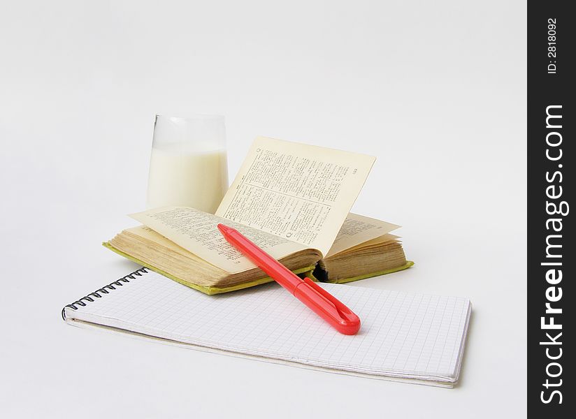 Notebook, the dictionary, the red pen and glass with milk on a white background. Notebook, the dictionary, the red pen and glass with milk on a white background.