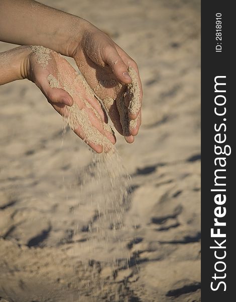 Girl pouring fine sand from two hand on beach