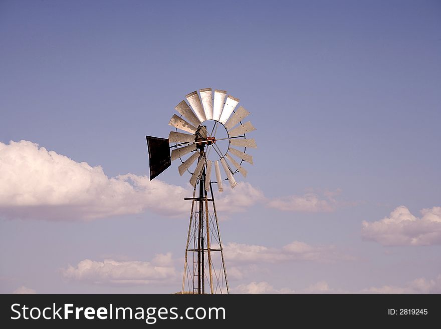 Windmill on clear blue sky with few clouds