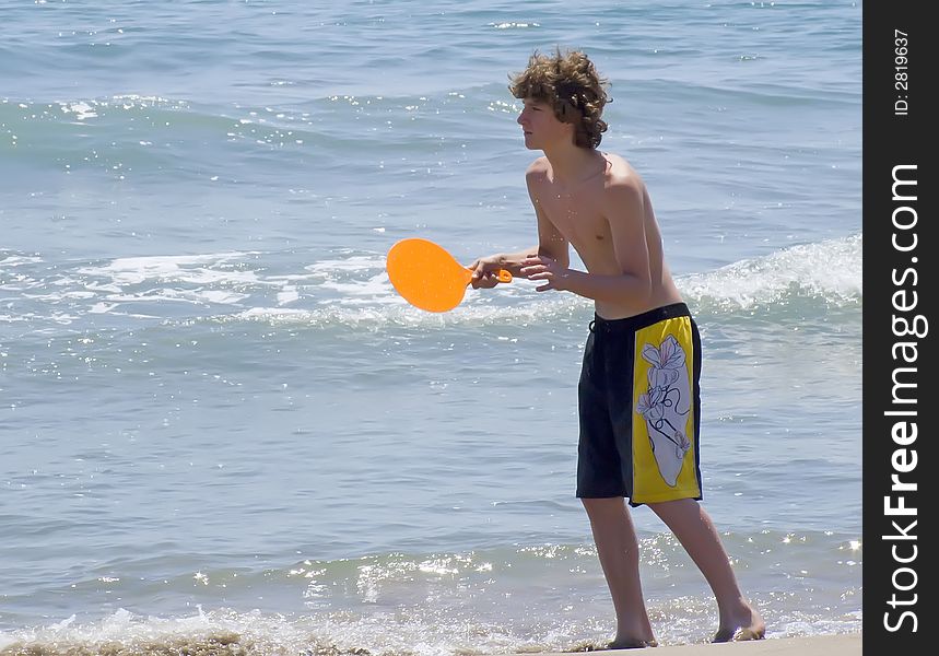 Young man playing beachball at the shore