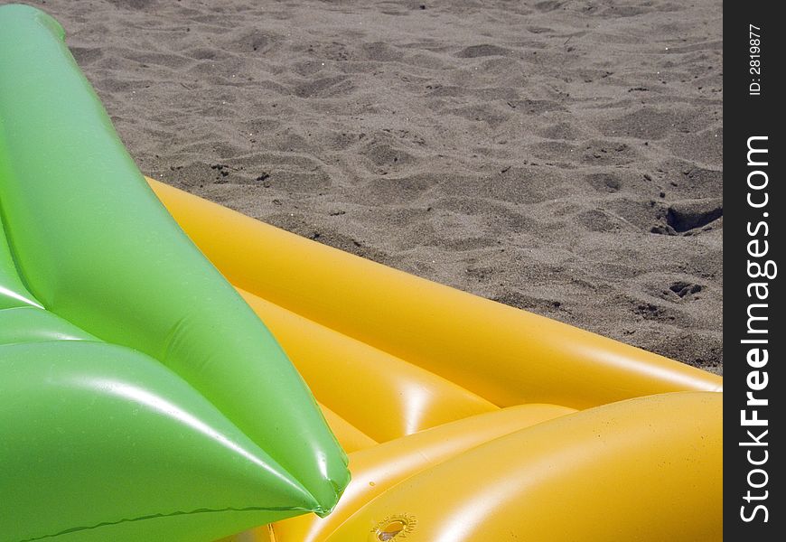 Two colored air mattrasses on the beach