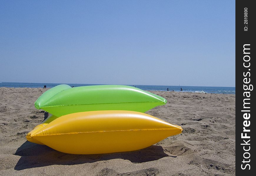 Two colored air mattrasses on the beach