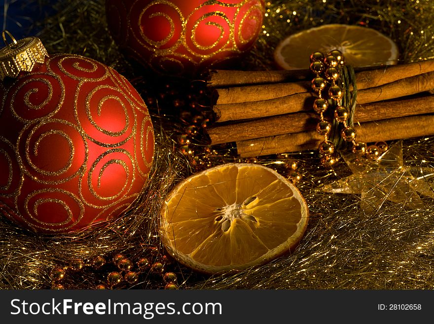 Red christmas ball, cinnamon,   orange and beads on gold background