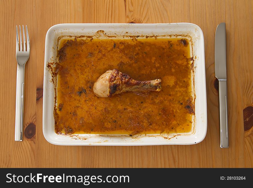 Roasted chicken thigh laying on plate in gravy