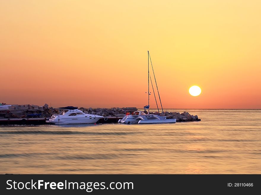 Small boats on anchor by the rocky sea shore in the evening. Small boats on anchor by the rocky sea shore in the evening