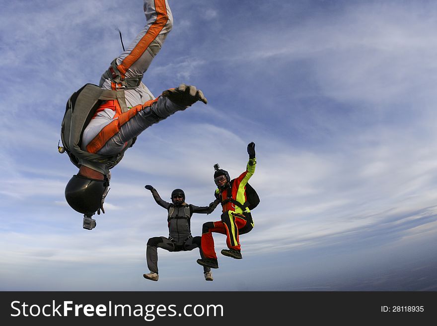 Three parachutists perform freestyle figures in free fall. Three parachutists perform freestyle figures in free fall.