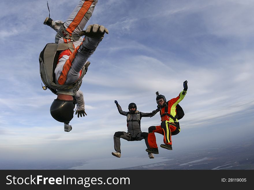 Three parachutists perform freestyle figures in free fall. Three parachutists perform freestyle figures in free fall.
