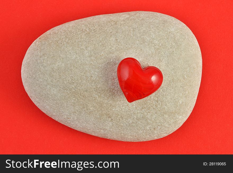 Red heart, on stone, on red background.