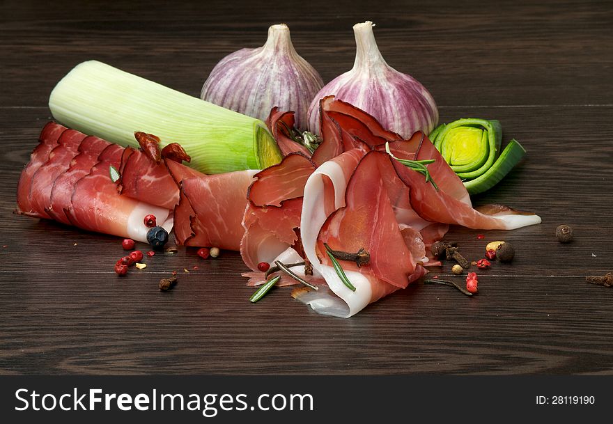 Arrangement of Thin Slices of Jamon, Garlic, Leek and Spices close up on Dark Wood background. Arrangement of Thin Slices of Jamon, Garlic, Leek and Spices close up on Dark Wood background