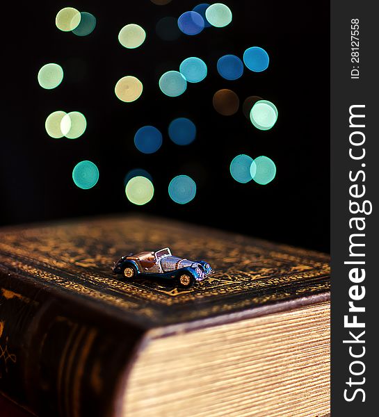 Old book and miniature car on bokeh lights background