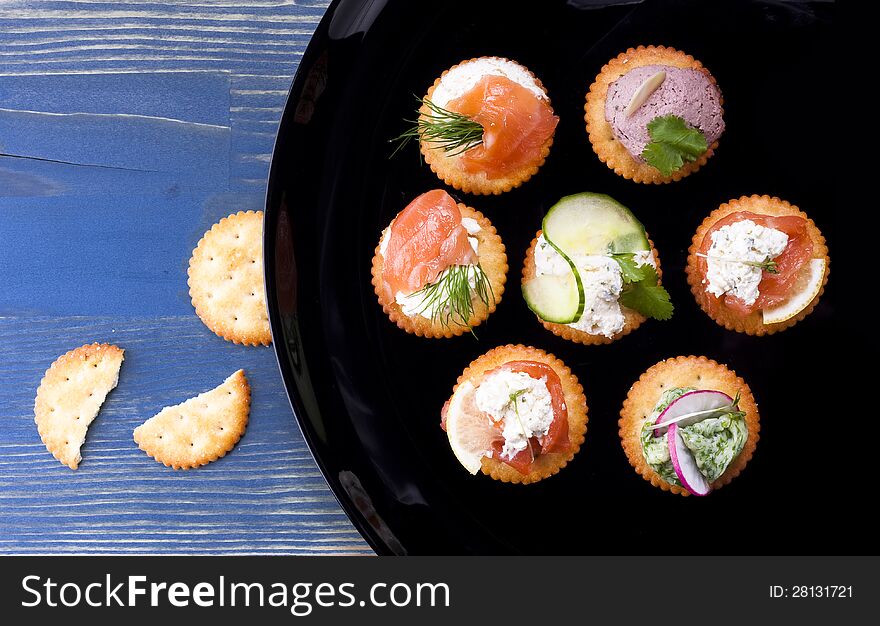 Light snack from various ingredients with soft cheese and herbs on crackers.