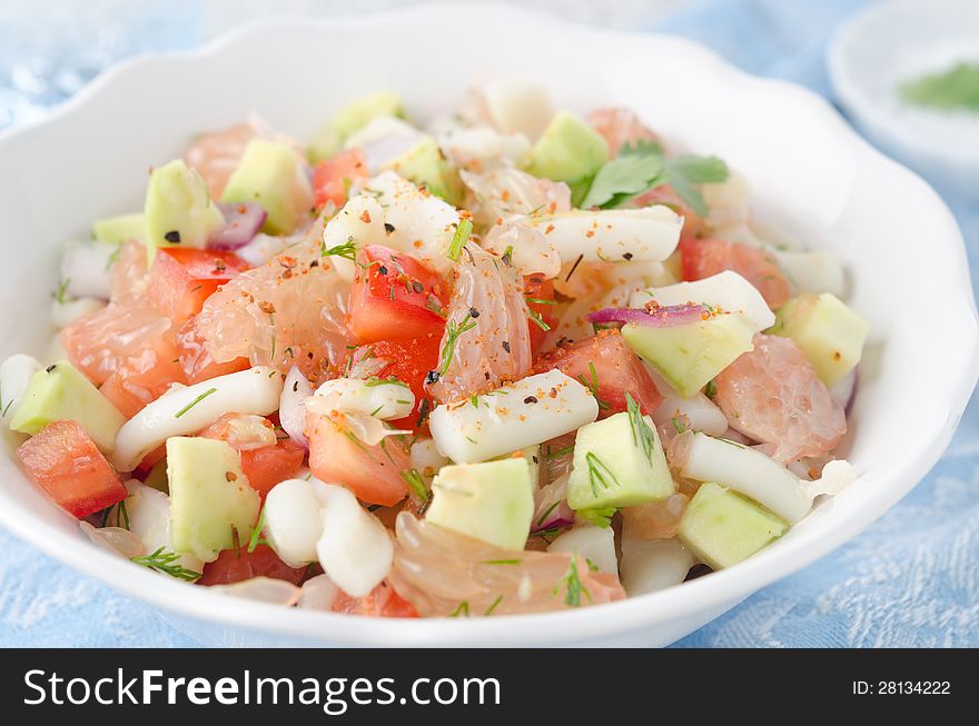 A bowl of salad with squid, avocado and grapefruit, closeup horizontal