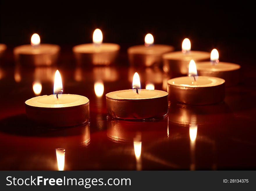Set of lighting candles in a row on dark background. Set of lighting candles in a row on dark background