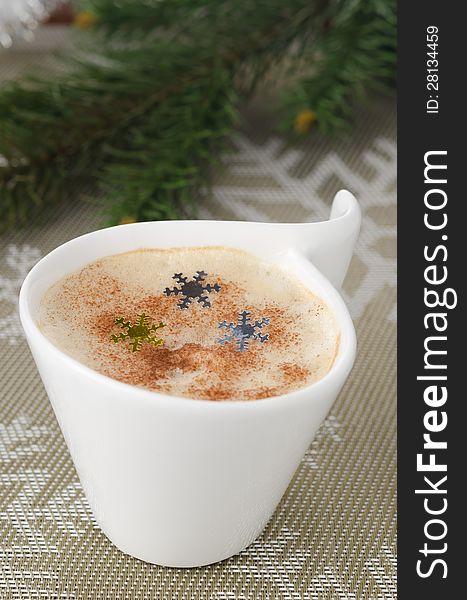 Cup of cappuccino on the table, fir branches in the background