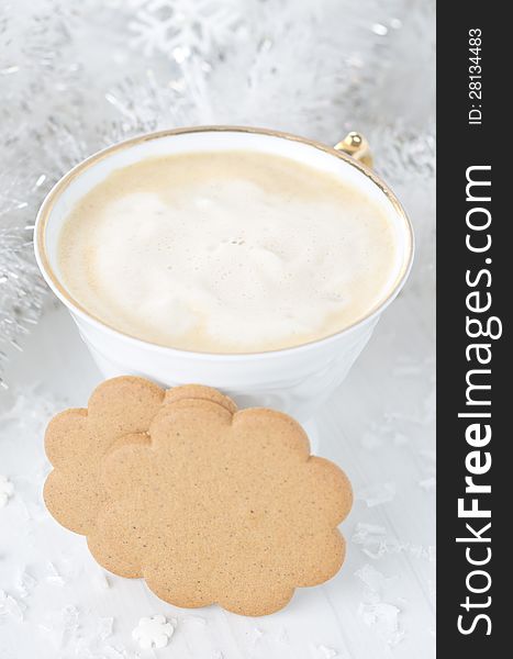 Ginger biscuits, cup of cappuccino, Christmas tinsel on a white background