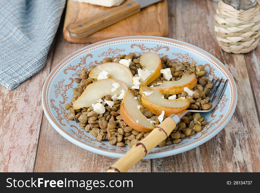 Lentil salad with caramelized pears and Roquefort cheese on a blue plate, horizontal