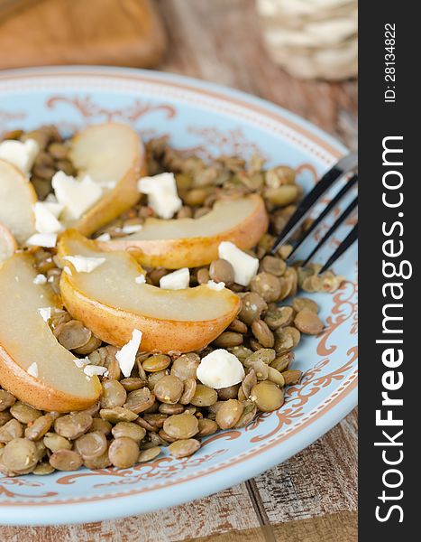 Lentil salad with caramelized pears and Roquefort cheese on a blue plate, closeup. Lentil salad with caramelized pears and Roquefort cheese on a blue plate, closeup