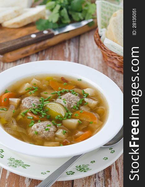 Plate of vegetable soup with meatballs on the wooden table vertical