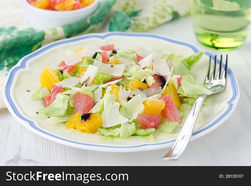 Salad with grapefruit, oranges, lettuce and cheese on a plate close-up. Salad with grapefruit, oranges, lettuce and cheese on a plate close-up