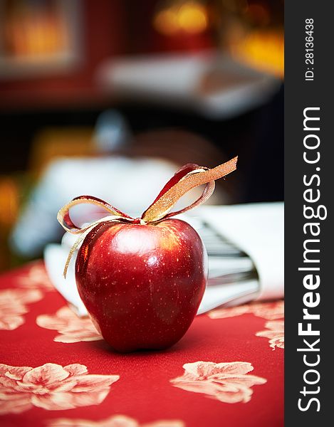 Red apple with bow on table