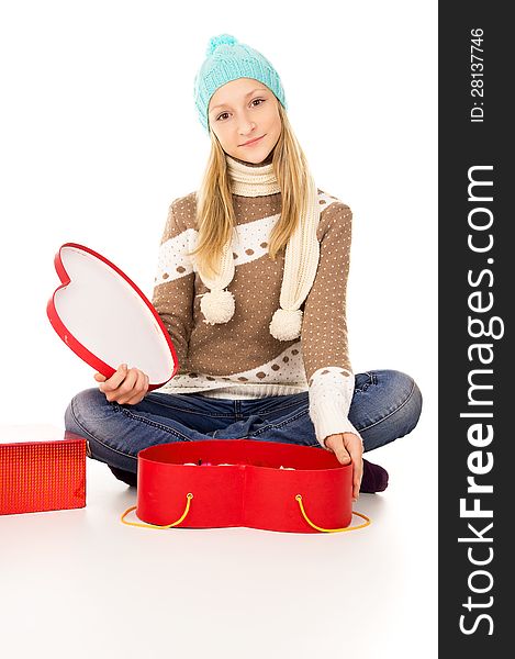 Girl in winter hat sitting with gift boxes