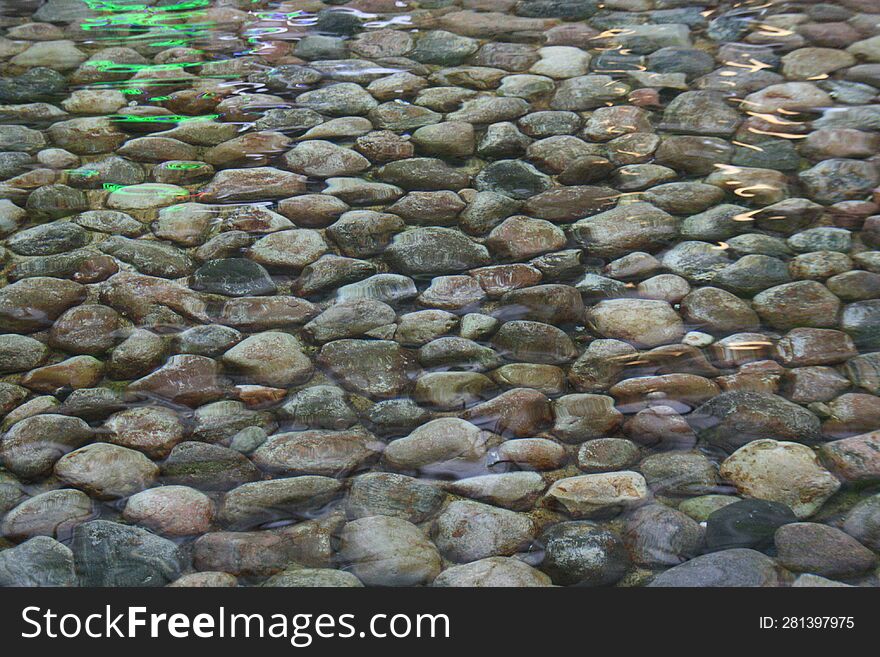 Background of stones with water and colored reflections.