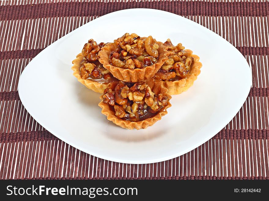 Walnut cakes in pyramid on white dish over brown mat