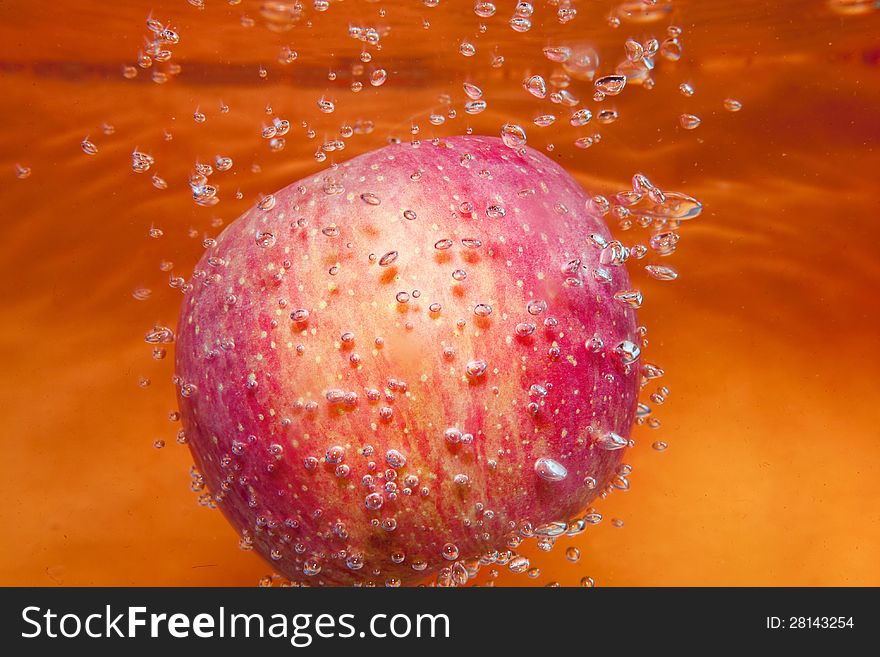 Red apple in water with bubbles