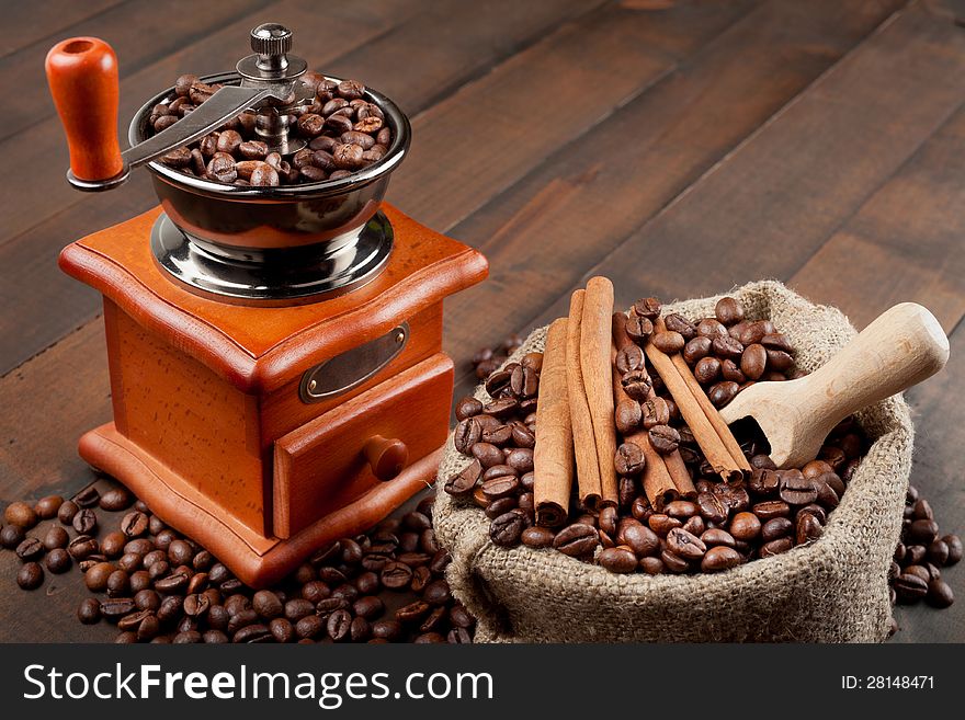 Coffee grinder and sack with coffee beans on wooden table