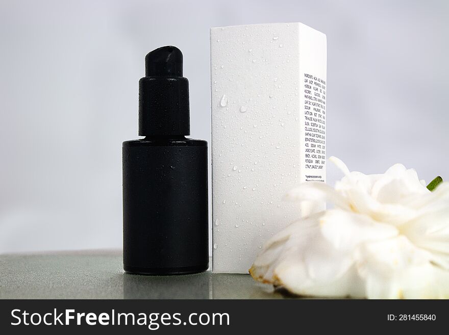 Product Photo Of Black Bottle And White Box Of Natural Cosmetics, On A White Background With Camellia Flower