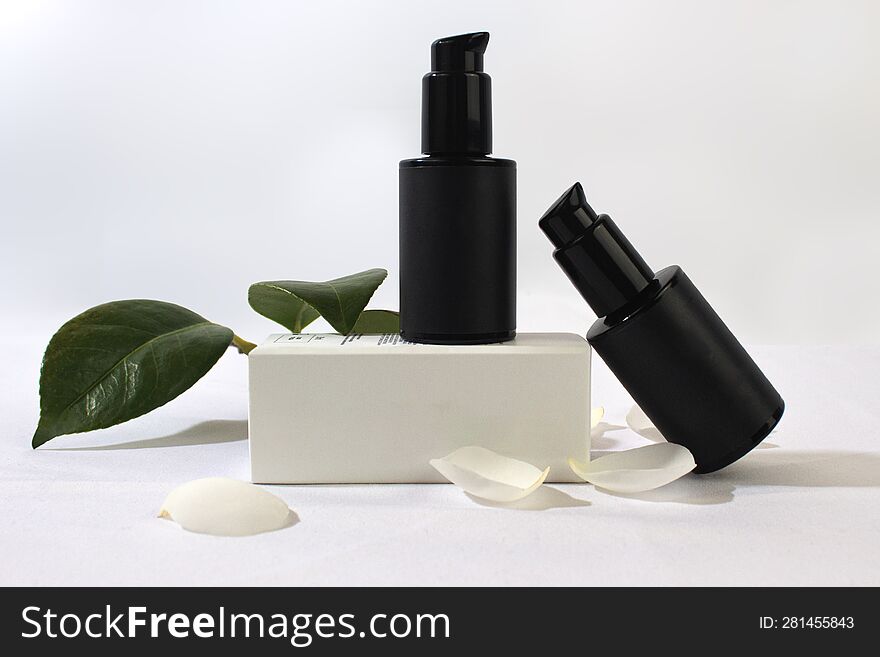 Product Photo Of White Boxes And Black Jars Of Natural Cosmetics, On A White Background With Camellia Leaves And Petals