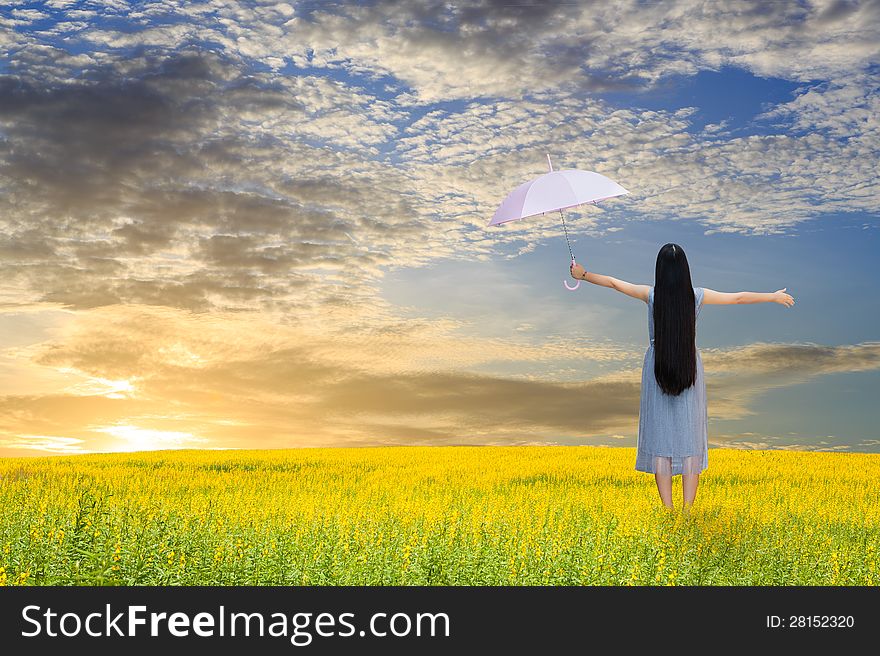 Asian girl holding pink umbrella in grass field and sunset