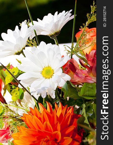 White, orange, and green wedding flower arrangements with burlap as the centerpieces for table settings at an outdoor reception. White, orange, and green wedding flower arrangements with burlap as the centerpieces for table settings at an outdoor reception.