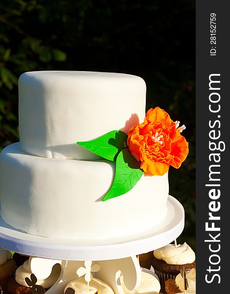 A simple wedding cake made of mostly white fondant and an orange and green flower. A simple wedding cake made of mostly white fondant and an orange and green flower.