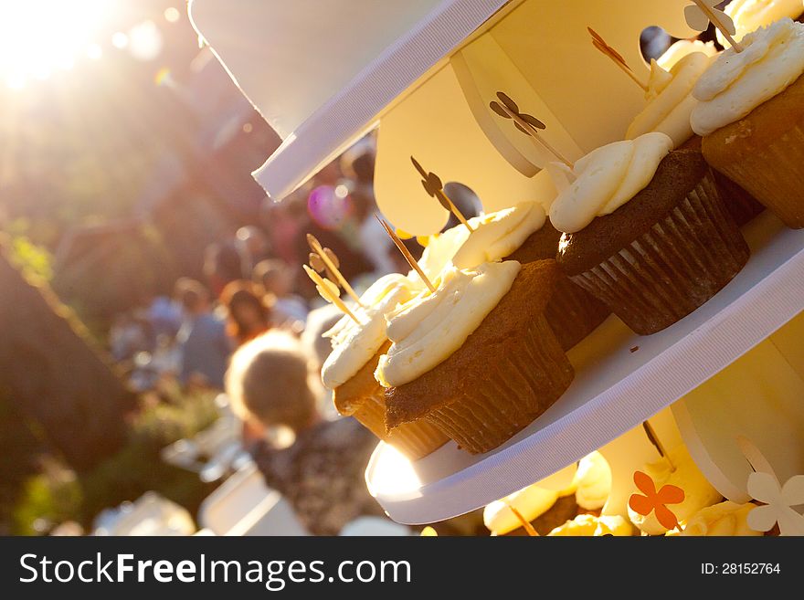 Three types of wedding cupcakes at a dessert recepition outdoors.