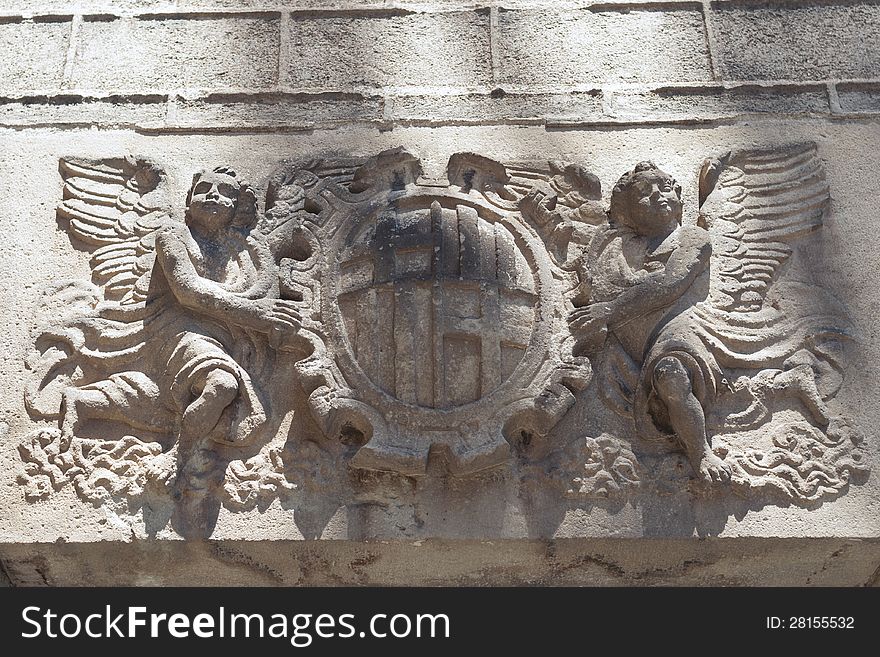 Medieval wall of Barcelona Cathedral with sculpture of two angels holding Coat of Arms. Medieval wall of Barcelona Cathedral with sculpture of two angels holding Coat of Arms