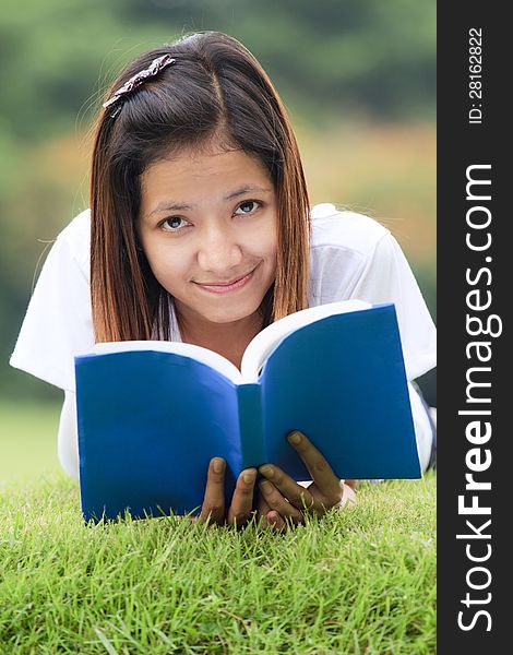 Young woman open a book, look to the camera and smile in outdoor. Young woman open a book, look to the camera and smile in outdoor