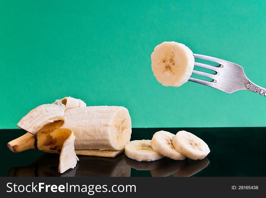 Half a banana and cut four pieces of one impaled on a fork on a black plate are. Half a banana and cut four pieces of one impaled on a fork on a black plate are