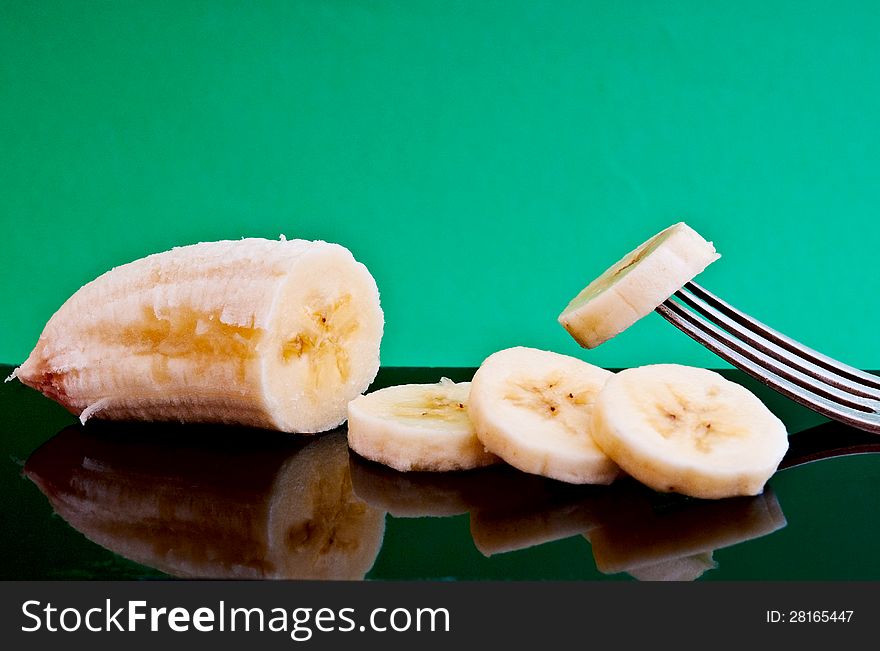 half a banana and cut four pieces of one impaled on a fork on a black plate are. half a banana and cut four pieces of one impaled on a fork on a black plate are