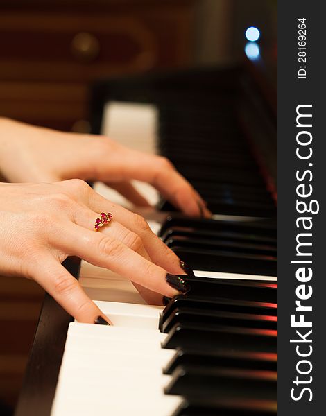 Girls hands playing the piano on dark background