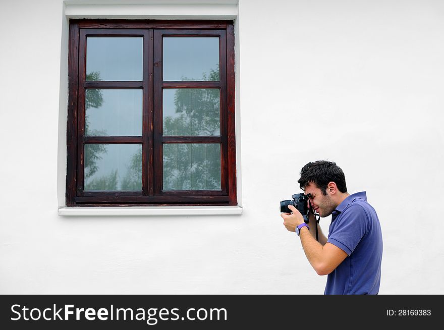 Photographer in blue shirt taking photos near a wooden window. Photographer in blue shirt taking photos near a wooden window.