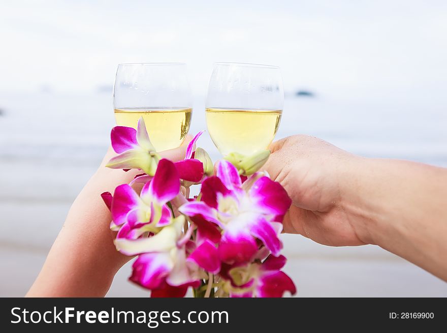 Two hands, glasses of champagne and a bouquet of orchids.