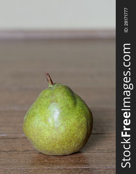 A single green pear on wooden table