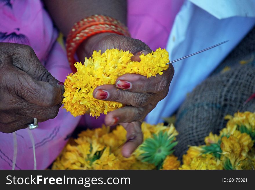 A flower seller making garland for the temple deities. A flower seller making garland for the temple deities