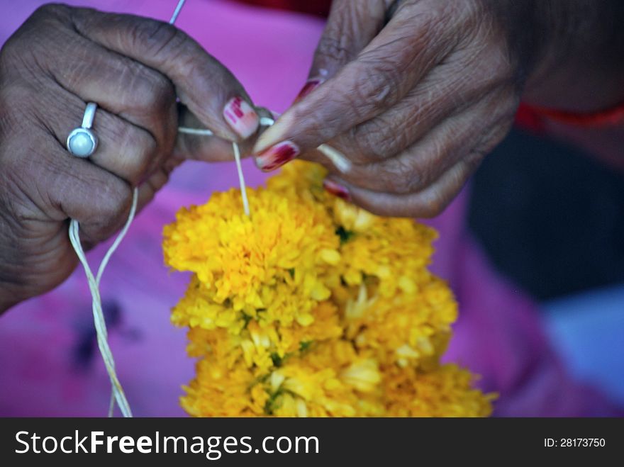 A flower seller making garland for the temple deities. A flower seller making garland for the temple deities